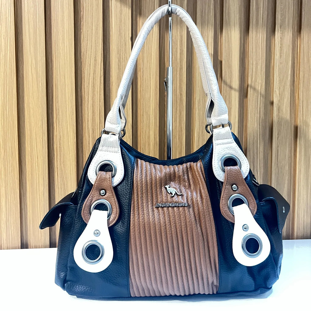 Front view of black and brown women's handbag with white handles and textured center panel