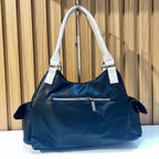 Back view of black women's handbag with zippered back pocket and white handles