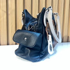 Side view of black women's handbag showing structured shape and side pocket