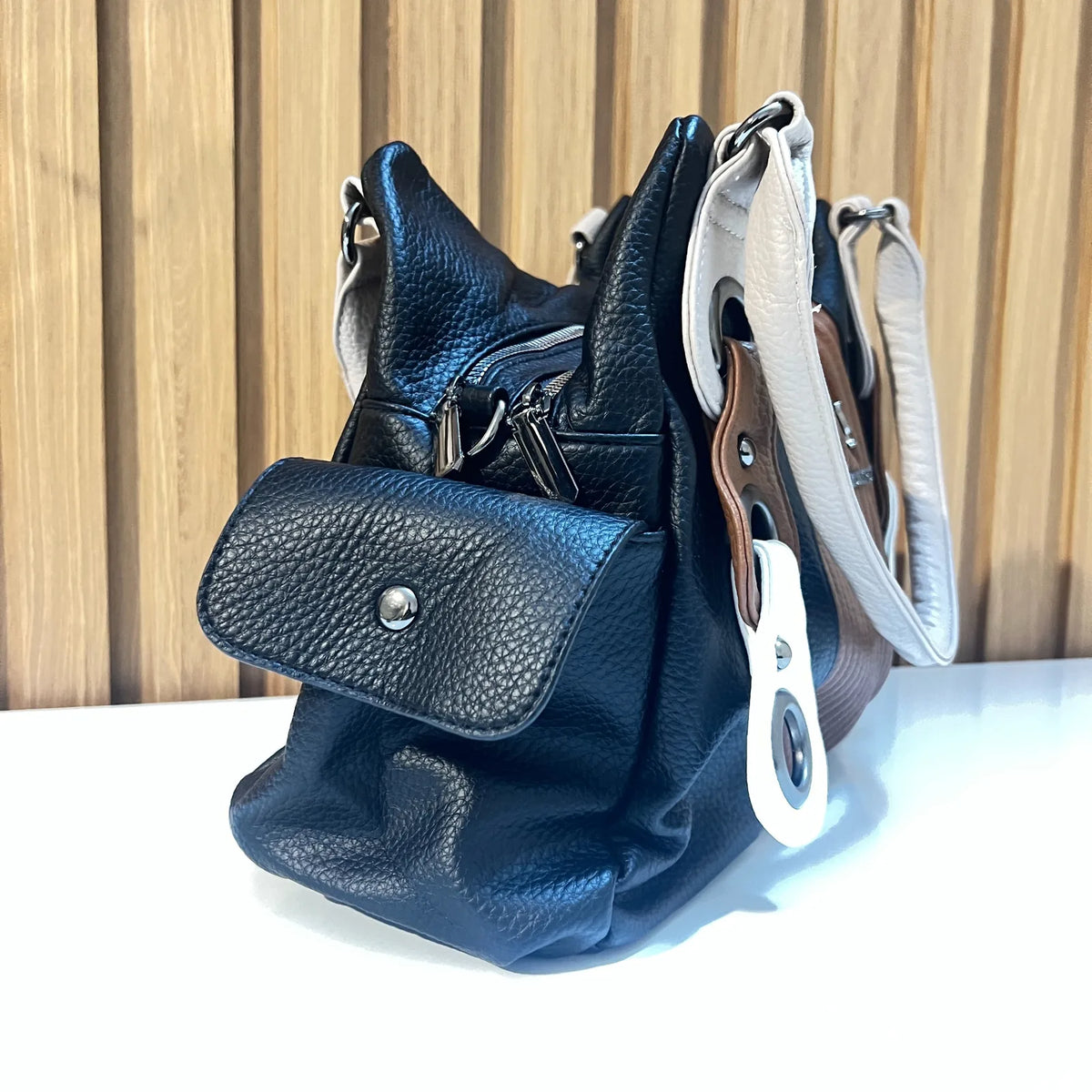 Side view of black women's handbag showing structured shape and side pocket