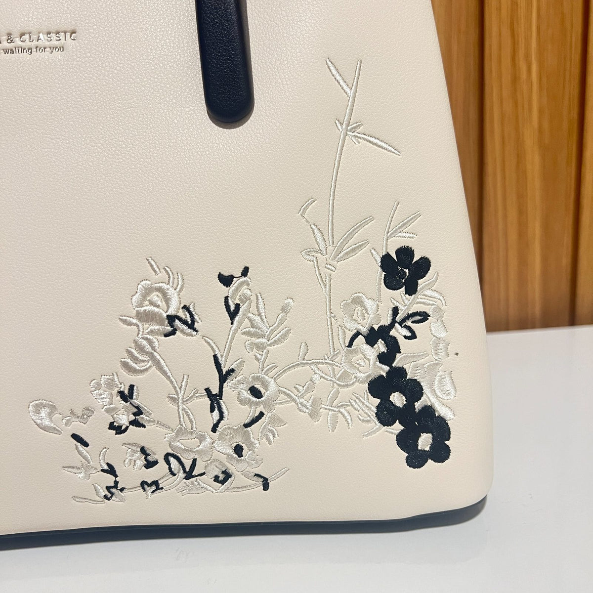 Cream handbag with black floral embroidery close up detail